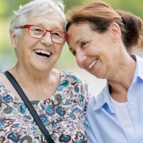 Happy senior woman and caregiver walking outdoors